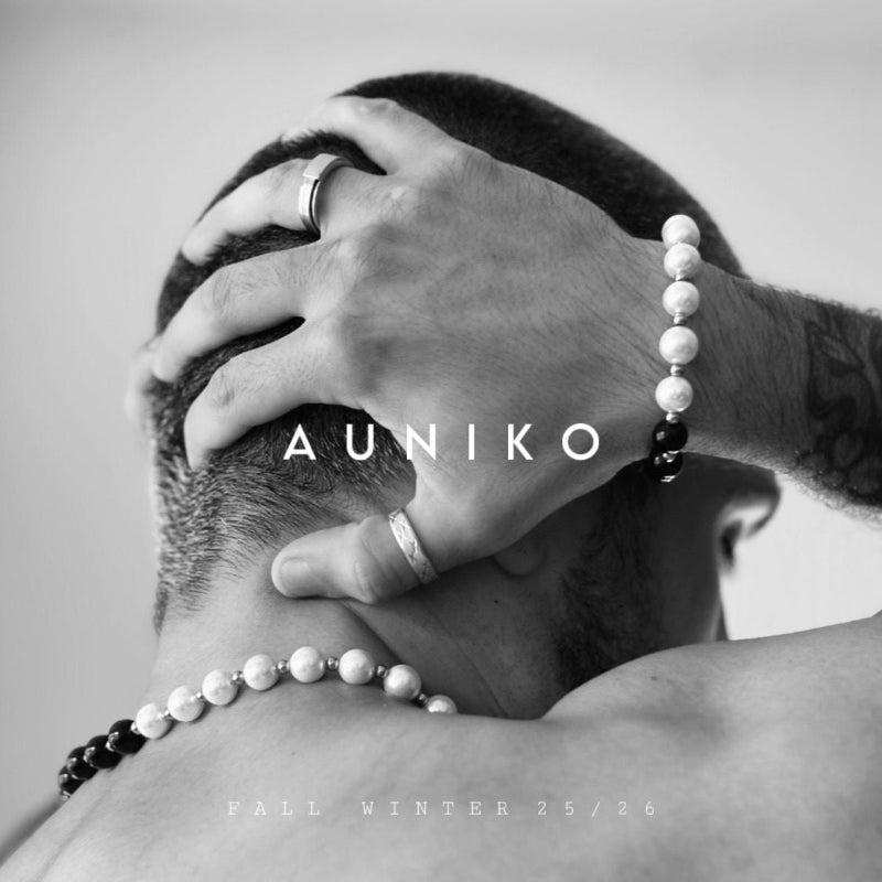 Person wearing a beaded necklace with 'Auniko' branding on a plain background